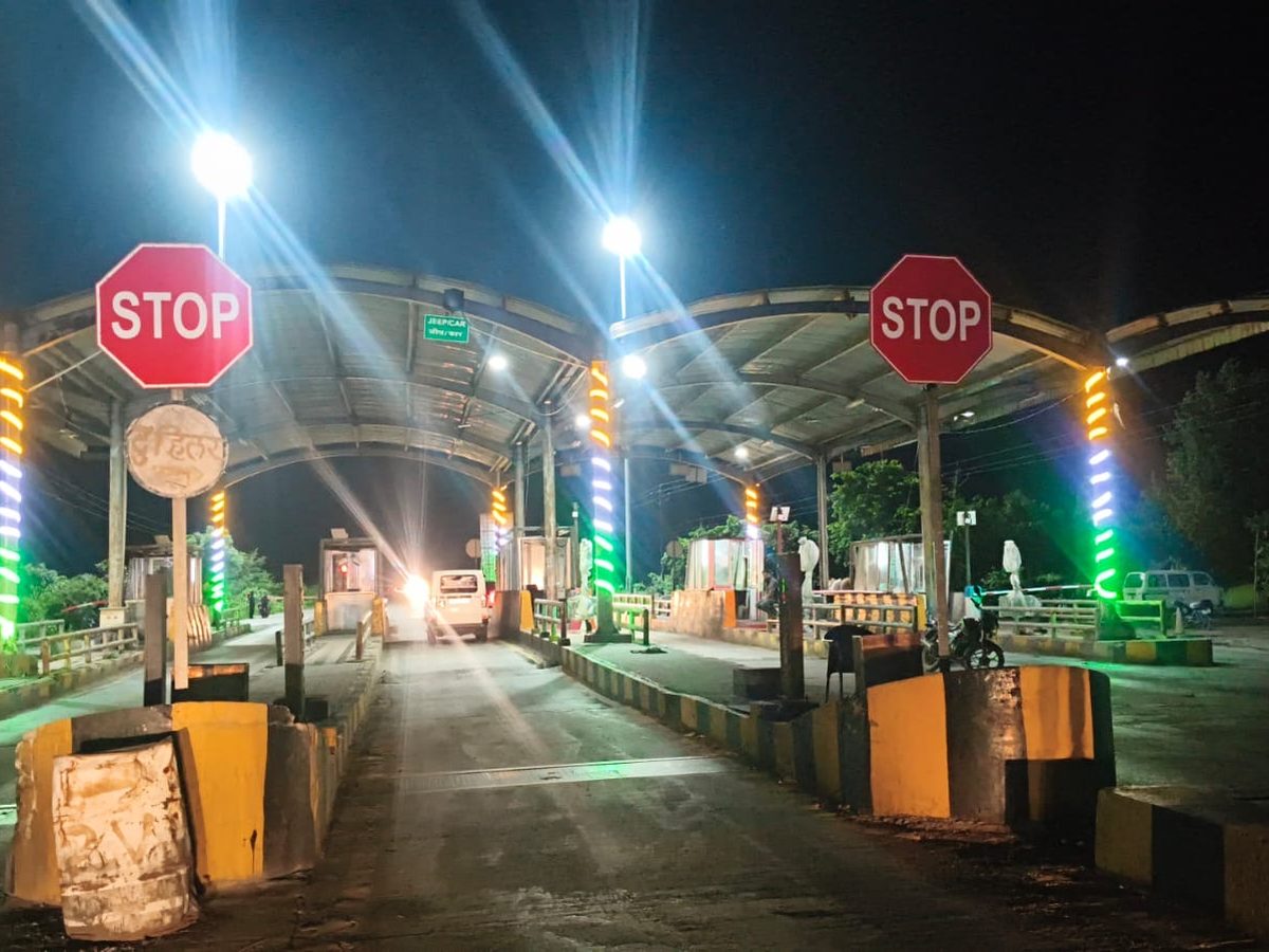 A toll plaza lit at night, with STOP signs at the lane entries