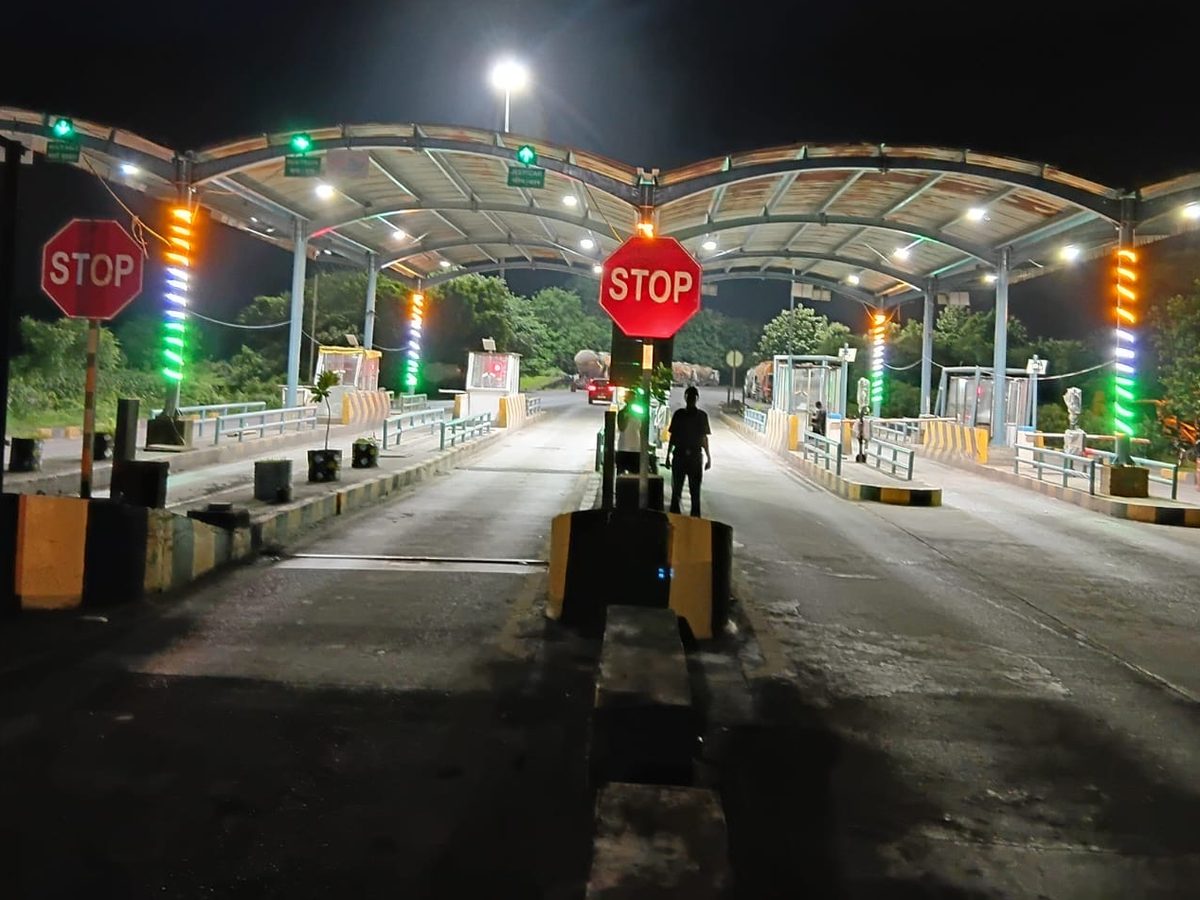 The lit canopy of a toll plaza at night, seen along the lanes